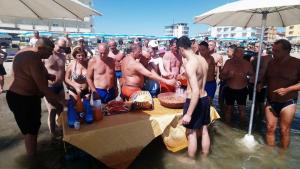 a group of men standing around a table in the water at Strand Hotel Colorado in Lido di Savio