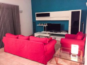 a living room with a red couch and a tv at Villa Son Remei in Punta Prima