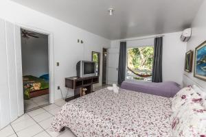 a bedroom with a bed and a tv in it at Hotel Mundaí Praia Camping e Est para Mh in Porto Seguro