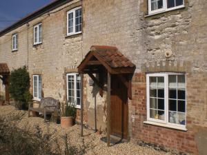 a brick building with a wooden door in front of it at Bluebell and Appletree Cottages in Hockwold cum Wilton