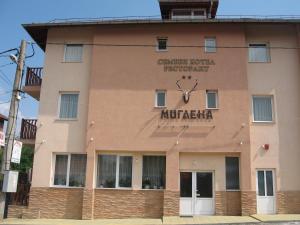 un bâtiment avec une horloge sur son côté dans l'établissement Family Hotel Miglena, à Govedartsi