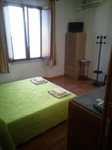 ein Schlafzimmer mit einem grünen Bett und einem Fenster in der Unterkunft Affitti Brevi Mamoiada Centro in Mamoiada