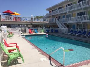 une piscine dans un hôtel avec des chaises et un bâtiment dans l'établissement Lollipop Motel, à North Wildwood