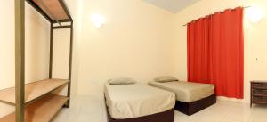 a bedroom with two beds and a red curtain at Connect Africa Apartments in Accra