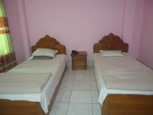 zwei Betten in einem kleinen Zimmer mit zwei Tischen in der Unterkunft Hotel Green Castle in Rangamati