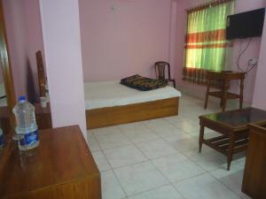 ein kleines Zimmer mit einem Bett, einem Tisch und einem Stuhl in der Unterkunft Hotel Green Castle in Rangamati