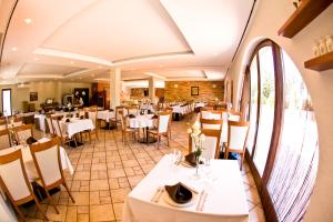 une salle à manger avec des tables et des chaises blanches dans l'établissement Budapest Airport Hotel Stáció Wellness & Konferencia, à Vecsés