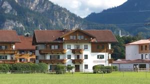 a group of buildings with a field in front of a mountain at Ferienwohnung Vormann in Schwangau