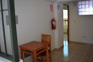 una habitación con una mesa y un extintor de incendios en la pared en Kuski Hospedaje, en Cusco