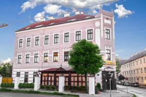 un edificio rosa con un árbol delante de él en Hotel MUSE, en Sankt Pölten