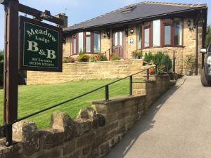 a sign in front of a house with a building at Meadow Lodge in Tideswell