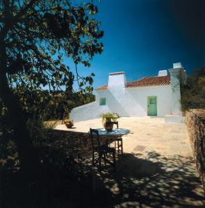 een tafel en stoelen voor een wit gebouw bij Horta de Torrejais in Moura