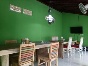 a dining room with green walls and a wooden table and chairs at Buyan Homestay in Sanur