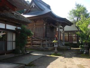 un edificio de madera con una bandera delante de él en Shukubo Kanbayashi Katsukane en Tsuruoka