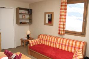 een woonkamer met een rode bank en een raam bij Résidence Le Chamois d'Or in Val Thorens