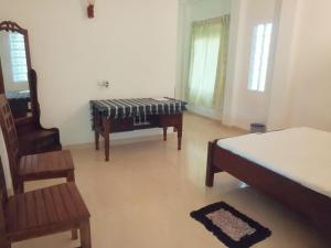 ein Schlafzimmer mit einem Bett, einem Stuhl und einem Klavier in der Unterkunft Sunrise Beach Inn in Ambalangoda