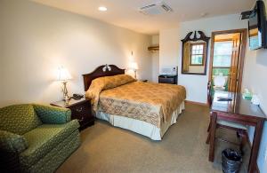 a bedroom with a bed and a couch and a chair at Sutton Inn in Elkton