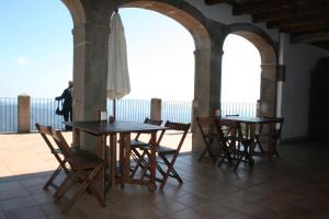 eine Terrasse mit 2 Tischen, Stühlen und einem Sonnenschirm in der Unterkunft Santuari de la Salut de Sant Feliu de Pallerols in Sant Feliu de Pallerols