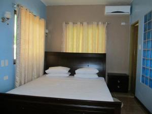 Schlafzimmer mit einem Bett mit weißer Bettwäsche und Kissen in der Unterkunft Ucoy Beach Resort in Libertad