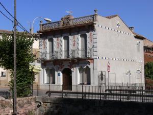 an old white building with a balcony on a street at Hostal Cal Pla in Sant Llorenc Savall