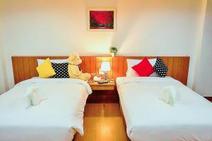 um quarto com duas camas com um urso de peluche sentado entre elas em The Terrace Khlongtoei em Hat Yai
