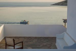 a boat in the water with a chair on a balcony at Oliaros seaside complex in Agios Georgios +30 photos