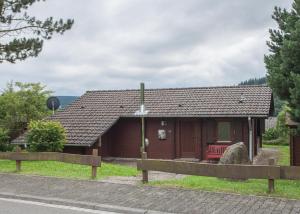 una piccola casa con una recinzione di fronte di Ferienhaus Auf der Heide 26-S, Winterberg-Niedersfeld a Winterberg