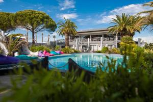 a swimming pool with palm trees in front of a building at Le Spinaker in Le Grau-du-Roi