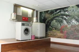 a laundry room with a washing machine and a painting at Beverly Commercial Motel in Luzhu