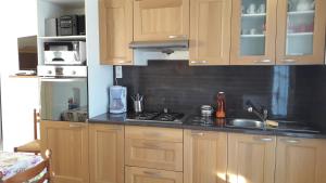 a kitchen with wooden cabinets and a sink and a stove at Ma Chaumiere Studio in Saint-Pierre-dʼOléron