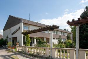 a white house with a wooden fence in front of it at Logis Hôtel Restaurant La Palette in Wettolsheim