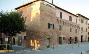 a large brick building on the side of a street at Affittacamere Caliani in Buonconvento