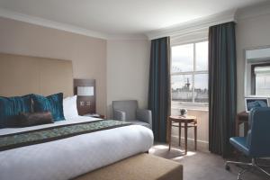 a hotel room with a bed and a desk and a window at Thistle London Piccadilly in London