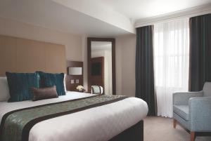 a hotel room with a large bed and a chair at Thistle London Piccadilly in London