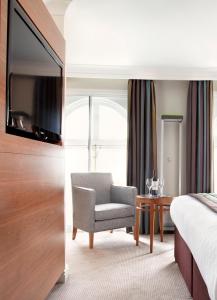 a hotel room with a chair and a television at Thistle London Piccadilly in London