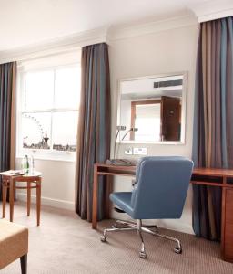 a room with a desk and a chair and a mirror at Thistle London Piccadilly in London