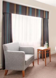 a living room with a chair and a table at Thistle London Piccadilly in London