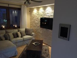 ein Wohnzimmer mit einem Sofa und einem TV an einer Backsteinwand in der Unterkunft Appartement St. Barbara in Trier