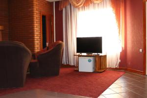 een woonkamer met een tv en stoelen en een raam bij Ideal Hotel in Vinnytsya