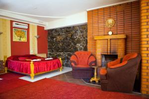 a bedroom with a bed and chairs and a fireplace at Ideal Hotel in Vinnytsya