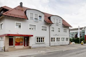 a white building with a red roof on a street at Central Hotel Friedrichshafen in Friedrichshafen