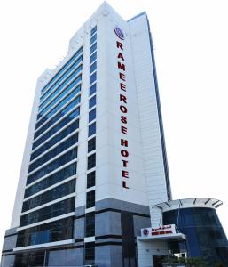 a tall white building with a red hotel sign on it at Ramee Rose Hotel in Dubai