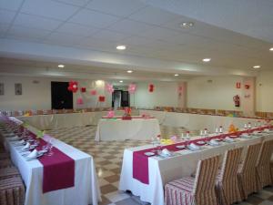 un salón de banquetes con mesas y sillas blancas y globos rojos en AHC Hoteles, en Cáceres