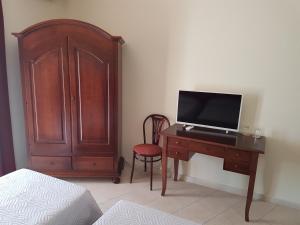 a bedroom with a desk with a tv and a wooden cabinet at Hotel Porto Azzurro in Giardini Naxos