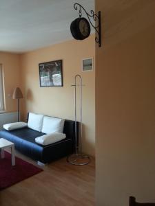 ein Wohnzimmer mit einem Sofa und einer Uhr an der Wand in der Unterkunft Kotany Apartman in Harkány
