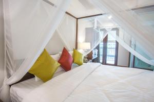 a bedroom with a white bed with yellow and red pillows at Night Bazaar Inn in Chiang Mai