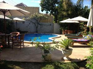 a swimming pool with a table and chairs and umbrellas at Rumah Saga in Gili Trawangan