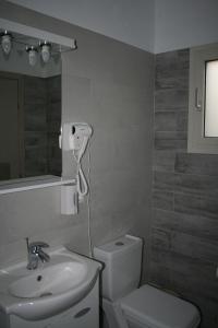 a bathroom with a sink and a toilet and a mirror at Emily's Apartments in Kassiopi