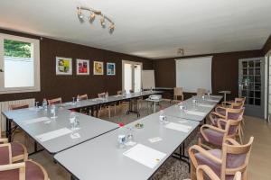 uma sala de reuniões com mesas longas e cadeiras em Logis Hotel Le Relais de Comodoliac em Saint-Junien