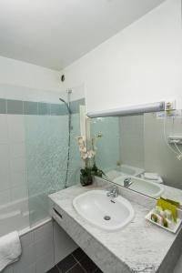 a bathroom with a sink and a tub and a mirror at Logis Hotel Le Relais de Comodoliac in Saint-Junien